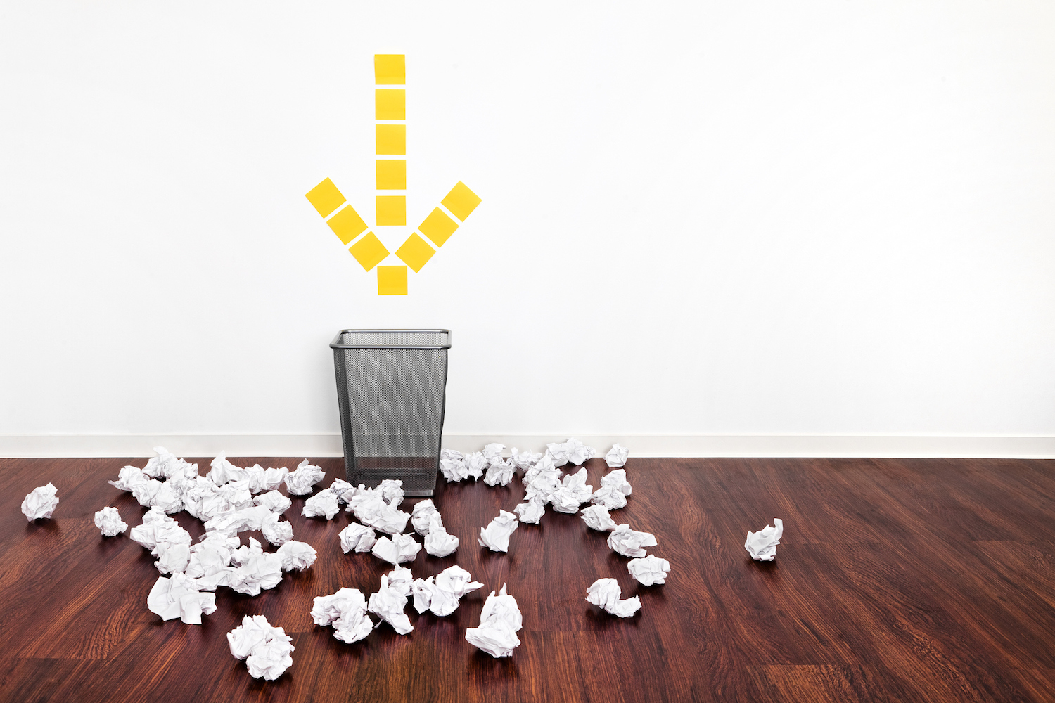 "Failure" Office Metaphor a trash can with a yellow arrow pointing at it surrounded by crumpled paper balls.
